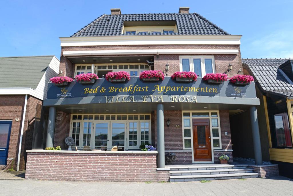 ein Backsteingebäude mit Blumen auf der Vorderseite in der Unterkunft Appartement Villa Eva Rosa in Wijk aan Zee