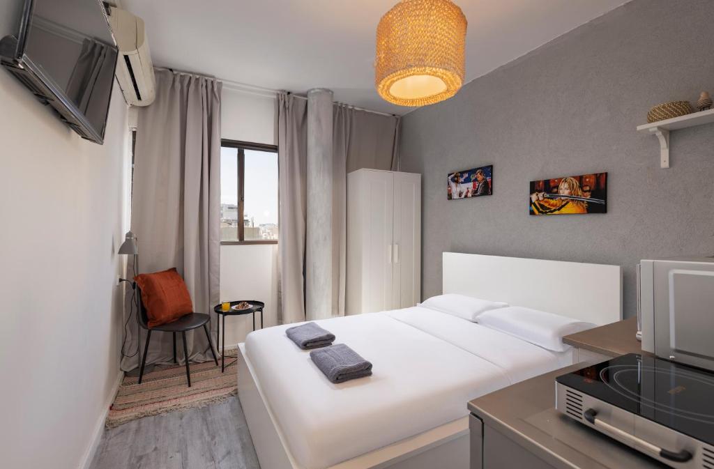 a hotel room with a white bed and a tv at Ran's Cozy Hotel Style apt in Tel Aviv