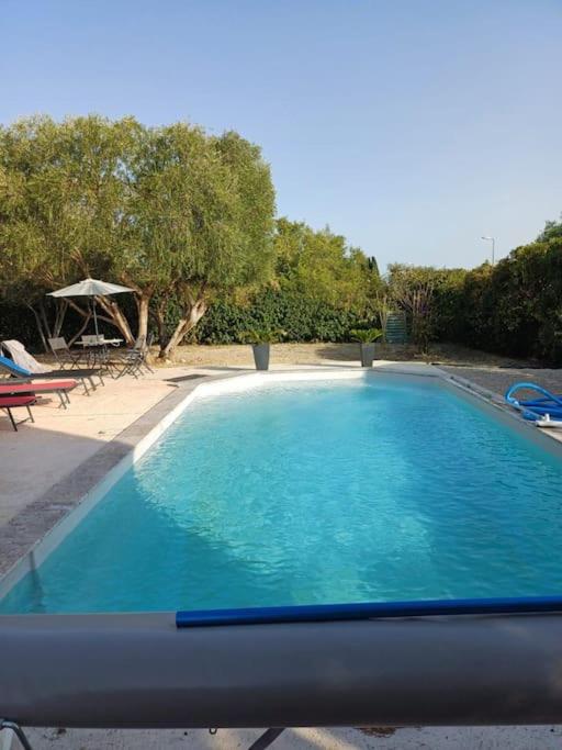 uma grande piscina azul com uma cadeira e guarda-sol em Le 7 em Servian