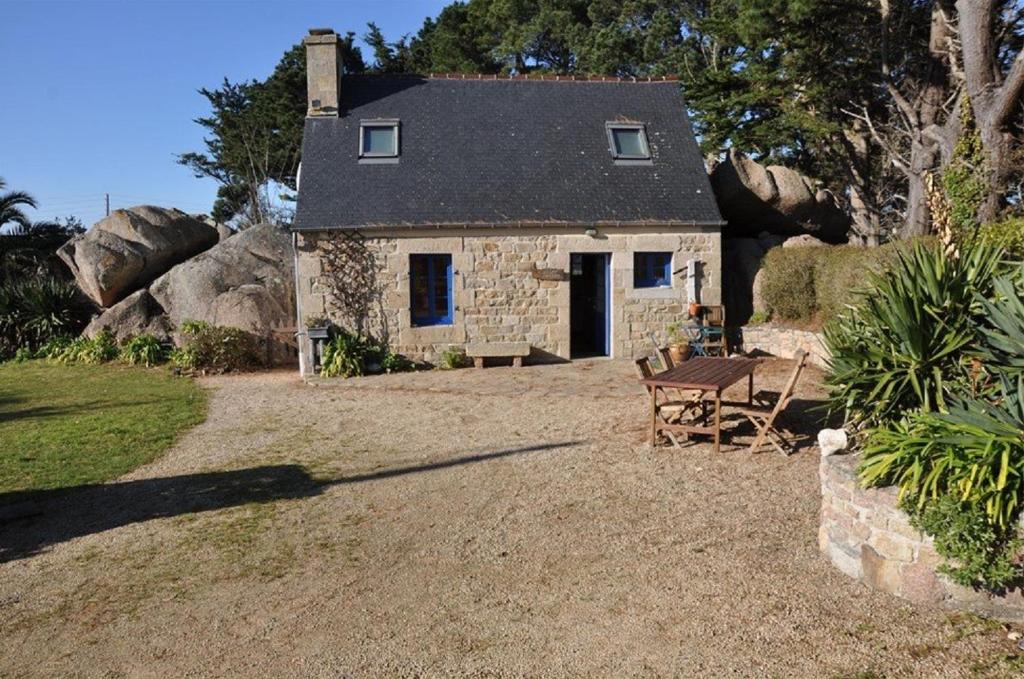een klein stenen huis met een bankje ervoor bij Maison bretonne 50m plage avec jardin et WIFI à TREGASTEL - Réf 413 in Trégastel