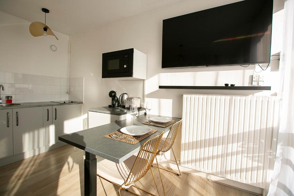 eine Küche mit einem Tisch mit Stühlen und einem TV an der Wand in der Unterkunft Relax studio in Le Mée-sur-Seine