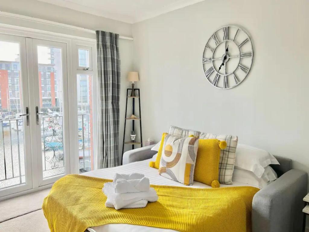 a bedroom with a bed with a yellow blanket and a clock at Pass the Keys Cosy Flat in Maritime Quarter in Swansea