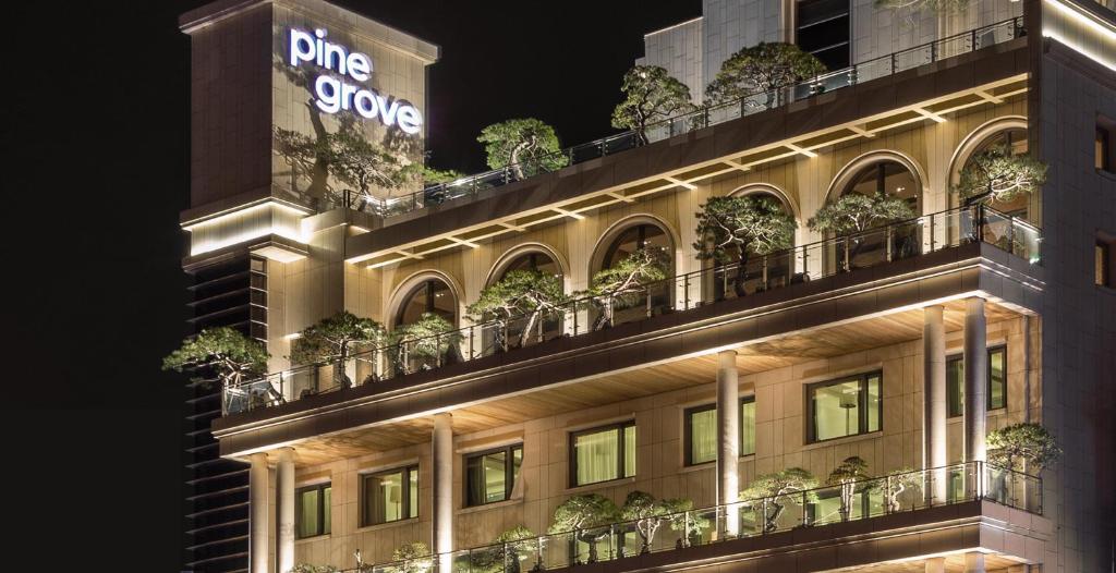 a building with potted plants on the balconies at night at Pinegrove Hotel in Gimhae