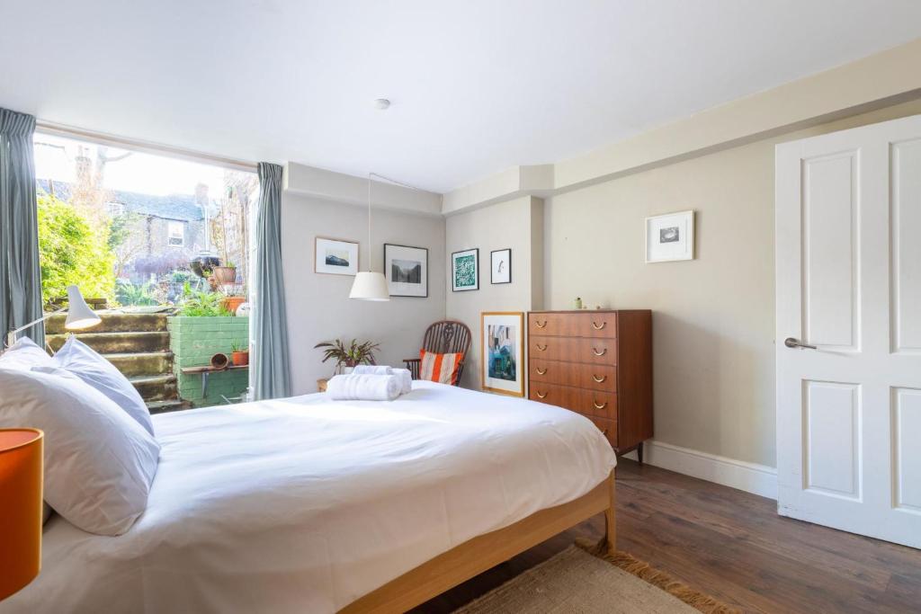 a bedroom with a large white bed and a window at Rustic Modern 1BD Flat wGarden Stoke Newington! in London