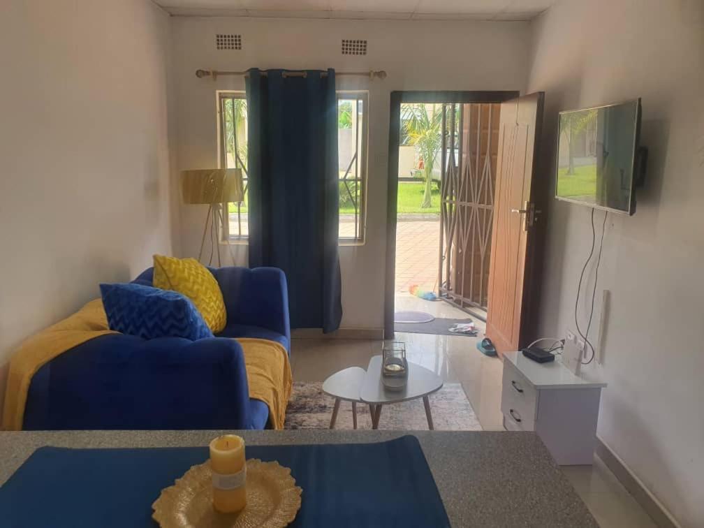 ein Wohnzimmer mit einem blauen Sofa und einem TV in der Unterkunft BlueView Apartments in Kitwe