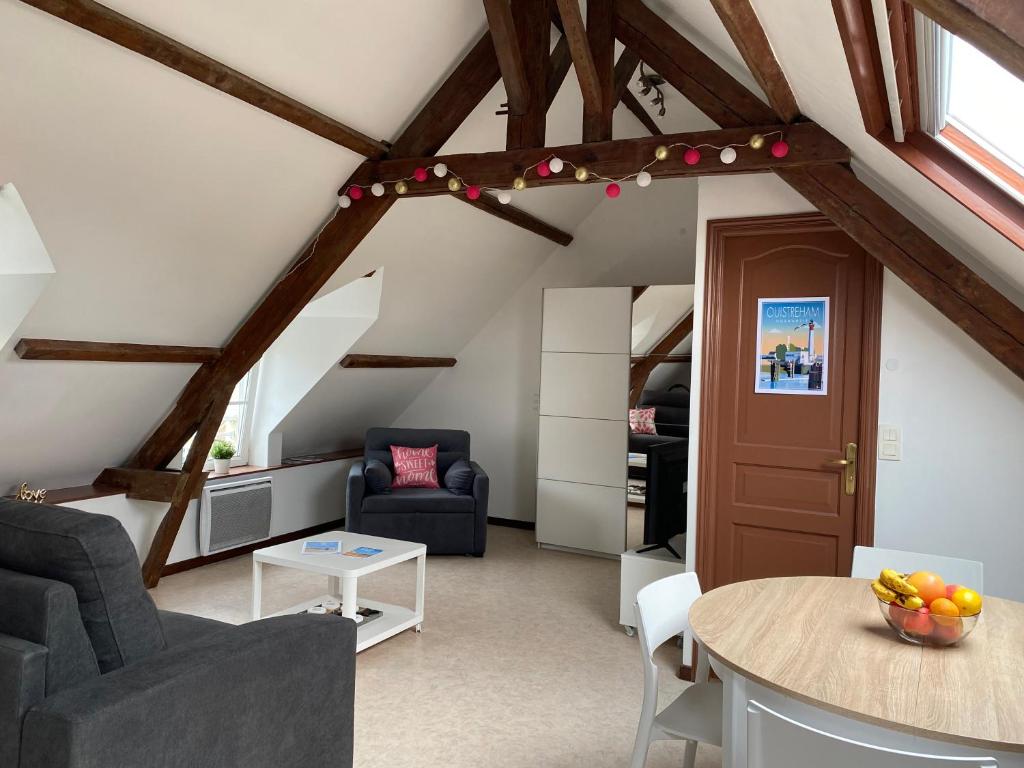 - un salon mansardé avec une table et des chaises dans l'établissement Charmant studio à Ouistreham, à Ouistreham