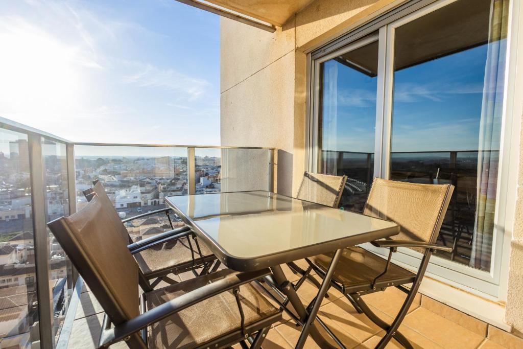 a glass table and chairs on the balcony of a building at Torres de la caseria con piscina in San Fernando