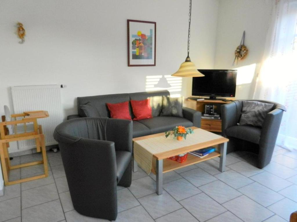 ein Wohnzimmer mit einem Sofa, 2 Stühlen und einem Tisch in der Unterkunft Ferienhaus Seehund in Krummhörn