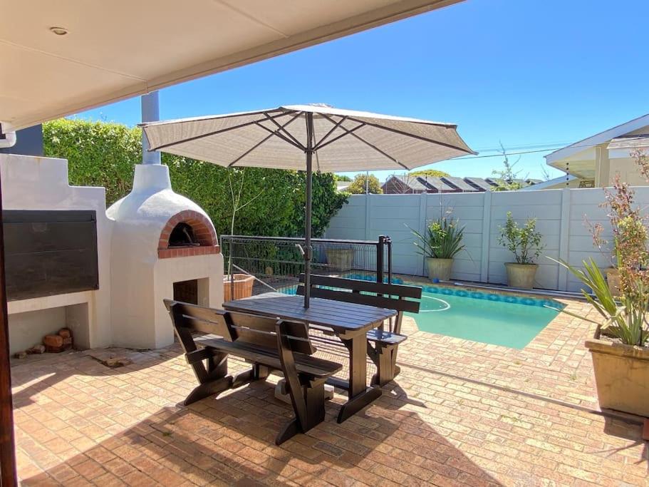 a patio with a picnic table and an umbrella at A Home in Timour Hall in Cape Town