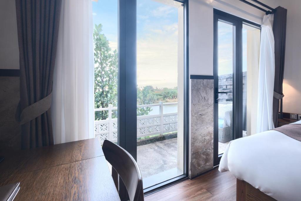 A small wooden desk overlooking the room’s balcony doors and outdoor greenery.