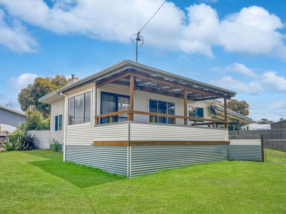 a house with a deck on a lawn at Wave Side Cottage Scamander Sleeps 5 in Scamander