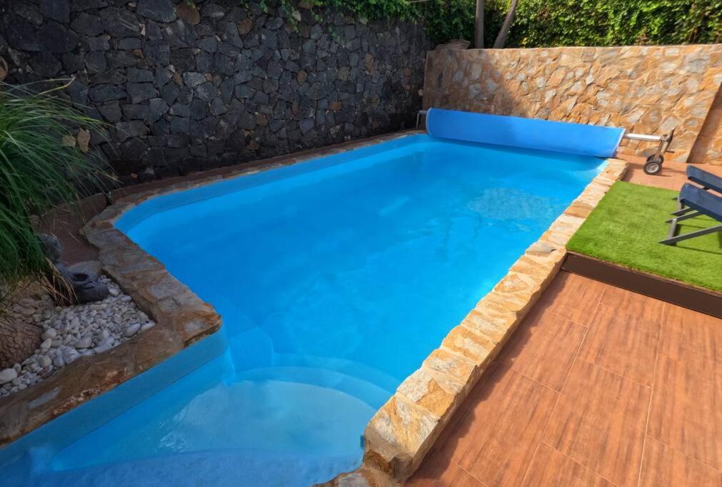 a swimming pool with blue water in a backyard at MoonLava: Apto, Piscina, WiFi in Yaiza