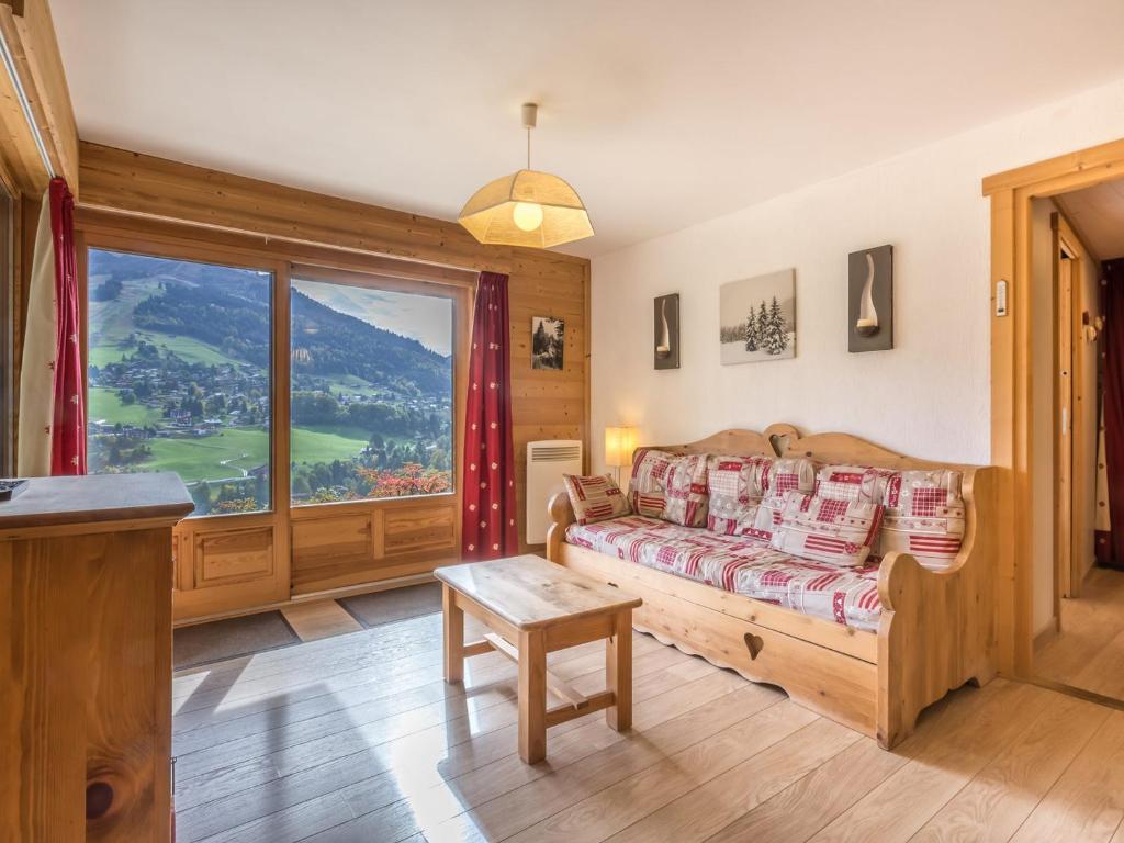 un salon avec un canapé et une grande fenêtre dans l'établissement Charmant 2 pièces avec coin nuit, parking et vue montagne à La Clusaz - FR-1-304-105, à La Clusaz