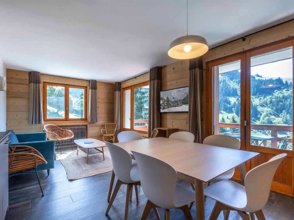 une salle à manger avec une table, des chaises et des fenêtres dans l'établissement 4 pièces près des pistes avec balcon - La Clusaz - FR-1-304-205, à La Clusaz