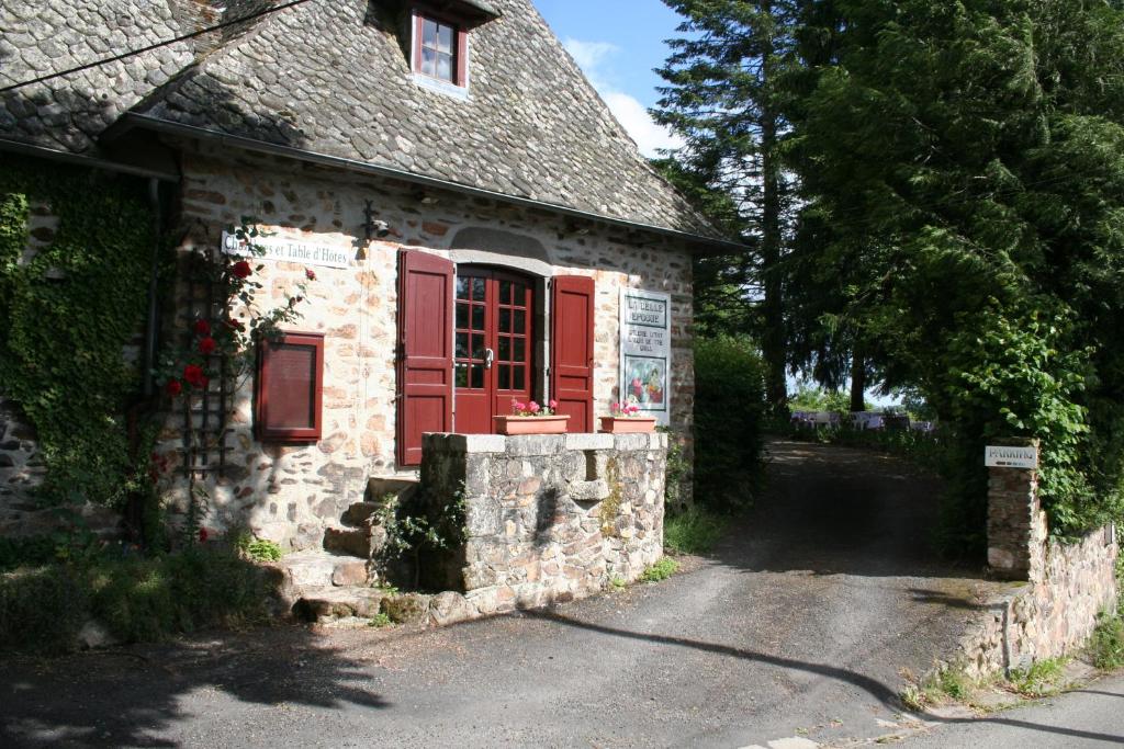 an old stone house with red doors and a driveway at La Belle Epoque in Sansac-de-Marmiesse