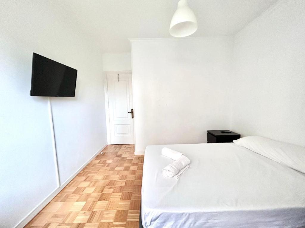 1 dormitorio con 1 cama blanca y TV de pantalla plana en VibesCoruña - Madariaga 41, en A Coruña