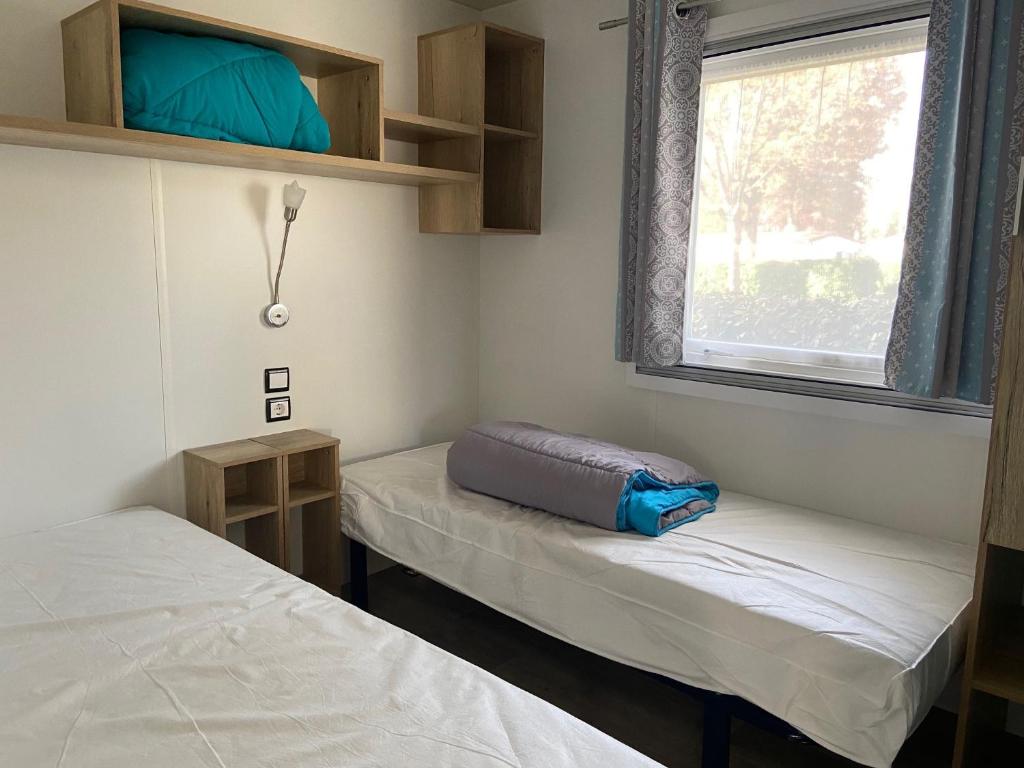 une chambre avec deux lits et une fenêtre dans l'établissement MOBIL HOME 2 CHAMBRES CLIMATISE, à Gastes 12 autres photos
