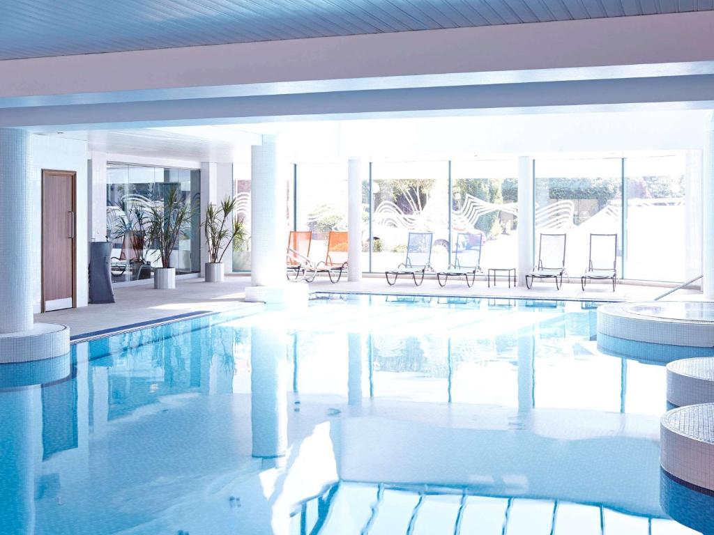 a large swimming pool with chairs in a building at Novotel Cardiff Centre in Cardiff