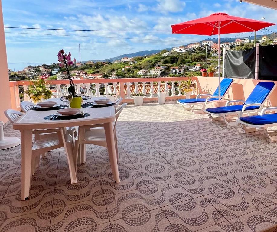 una mesa con sillas y una sombrilla en el balcón en Blue Paradise Apartment, en Ribeira Brava