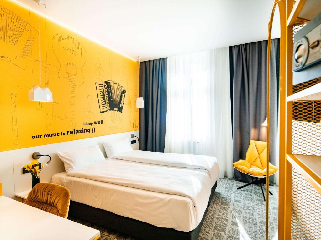 a hotel room with a bed and a yellow wall at Ibis Styles Sibiu Arsenal in Sibiu