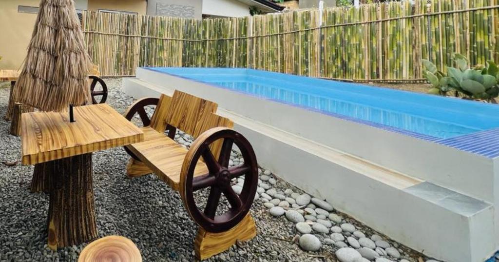 um banco de madeira ao lado de uma piscina em 2BR House in Elyu for 8 pax with Pool Access 
