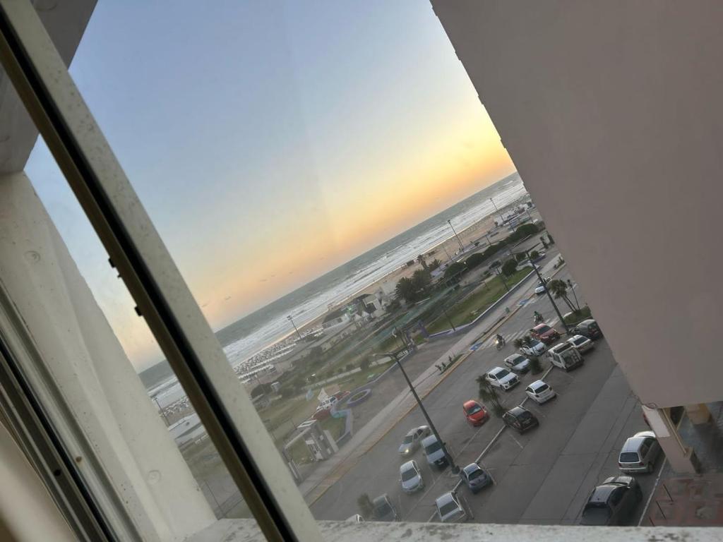 een raam met uitzicht op een parkeerplaats en de oceaan bij Marítima mono ambiente in Necochea