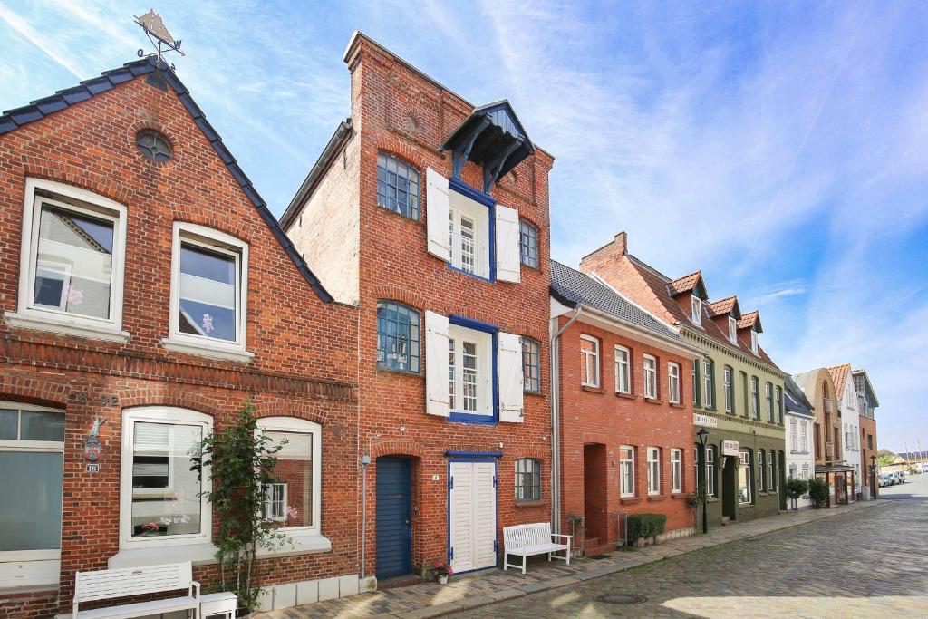 a red brick building with white windows on a street at Altes Kontorhaus Steuerbord in Husum