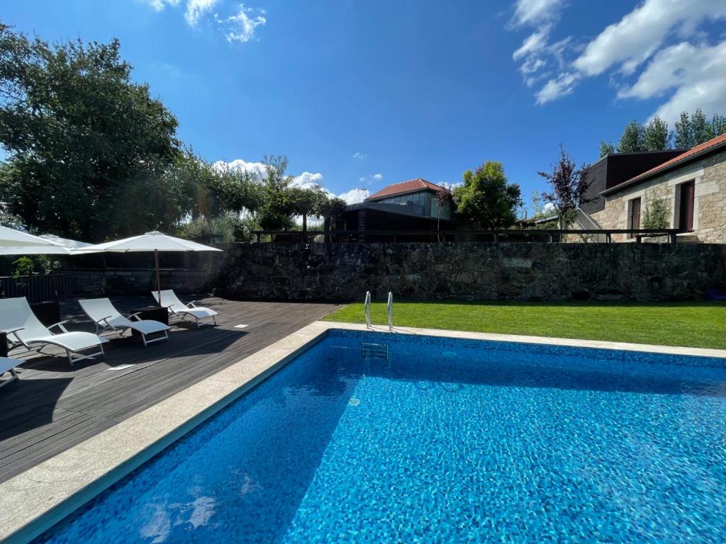 uma piscina com cadeiras e guarda-sóis ao lado de uma casa em Quinta do Fontão - Casa com piscina em Arcos de Valdevez