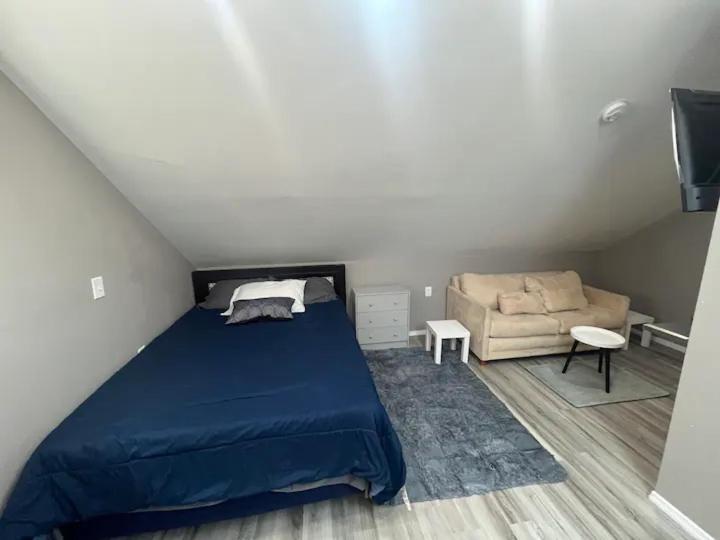 1 dormitorio con 1 cama azul y 1 sofá en 1 Bed Room Apartment near Airport, en Hillside