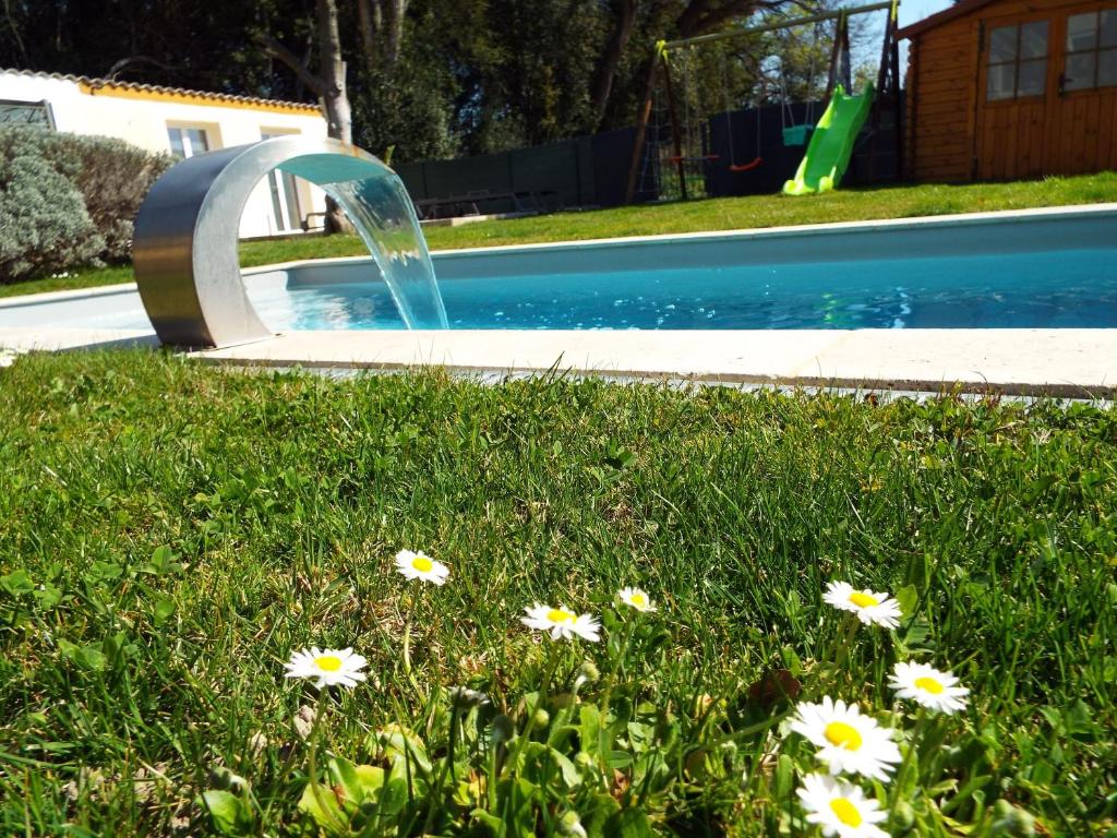 une fontaine dans l'herbe à côté d'une piscine dans l'établissement Maison de 2 chambres avec piscine partagee jardin clos et wifi a Avignon, à Avignon