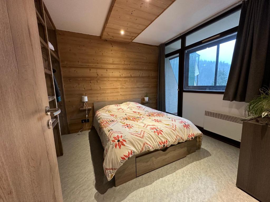 une chambre avec un lit dans une pièce avec une fenêtre dans l'établissement Appt pied des pistes 53m2 -5pers, à La Bresse