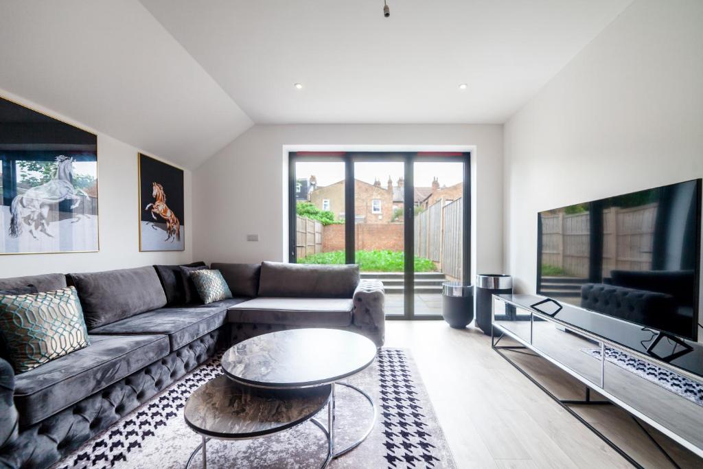 uma sala de estar com um sofá e uma televisão em Beautiful New Semi-detached 3 BR House wGarden em Brentford