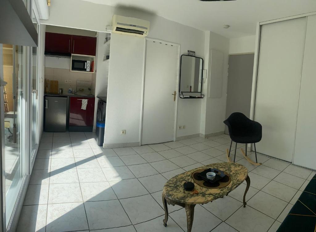 ein Wohnzimmer mit einem Tisch und einem Kühlschrank in der Unterkunft Studio avec terrasse in Montpellier