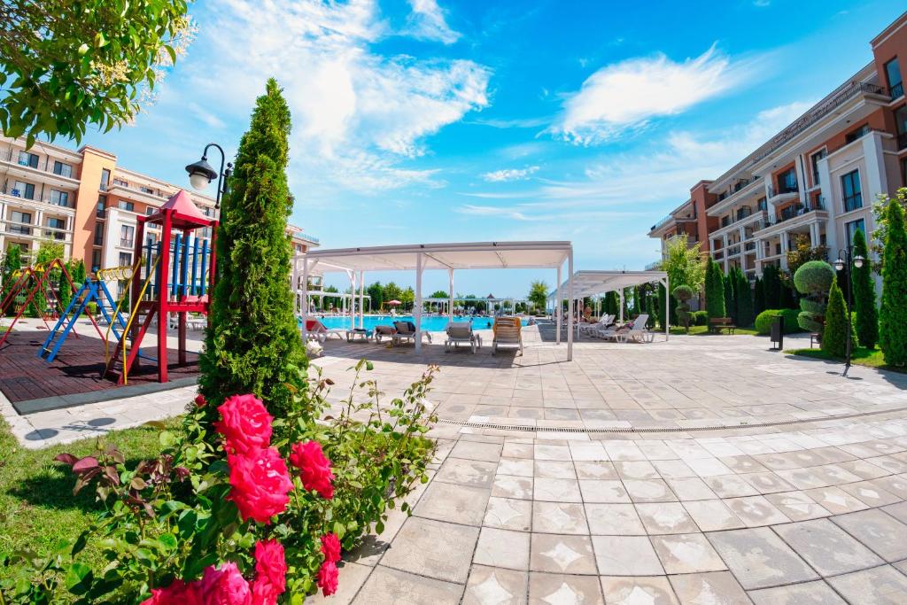 een park met een speeltuin en een paviljoen met bloemen bij Prestige Fort Beach - Full Board in Sveti Vlas