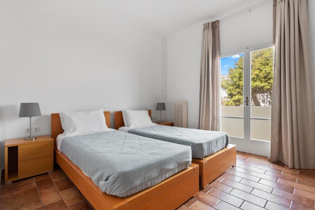 a bedroom with two beds and a large window at Hotel Roumani in Spetses