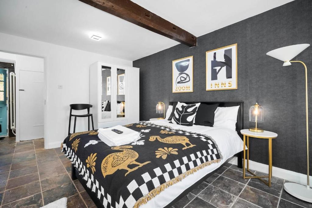a bedroom with a king sized bed with a black and gold blanket at Luxury,cosy Cottage with Hot Tub&Massage beds in Kidderminster