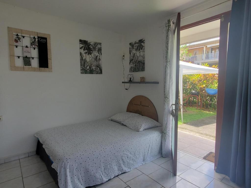 een slaapkamer met een bed in een witte kamer bij Studio en rez-de jardin clos à 4km de l'aéroport et proche de toutes les commodités in Le Lamentin