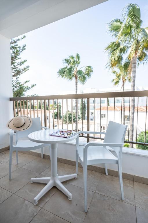 a white table and chairs on a balcony with palm trees at New Famagusta Hotel & Suites in Ayia Napa