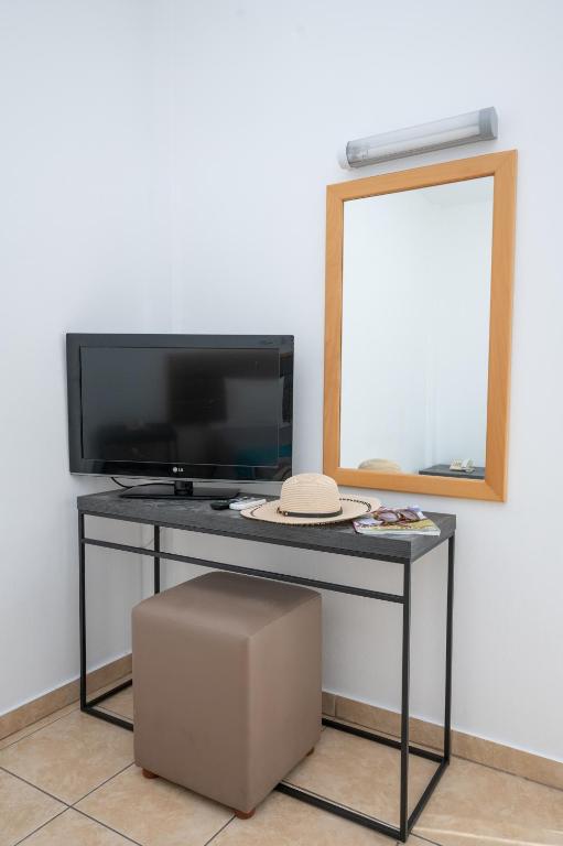 a table with a tv and a mirror and a stool at New Famagusta Hotel & Suites in Ayia Napa