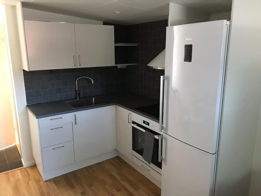 a kitchen with white cabinets and a refrigerator at Modernt boende med god tillgänglighet. in Alingsås