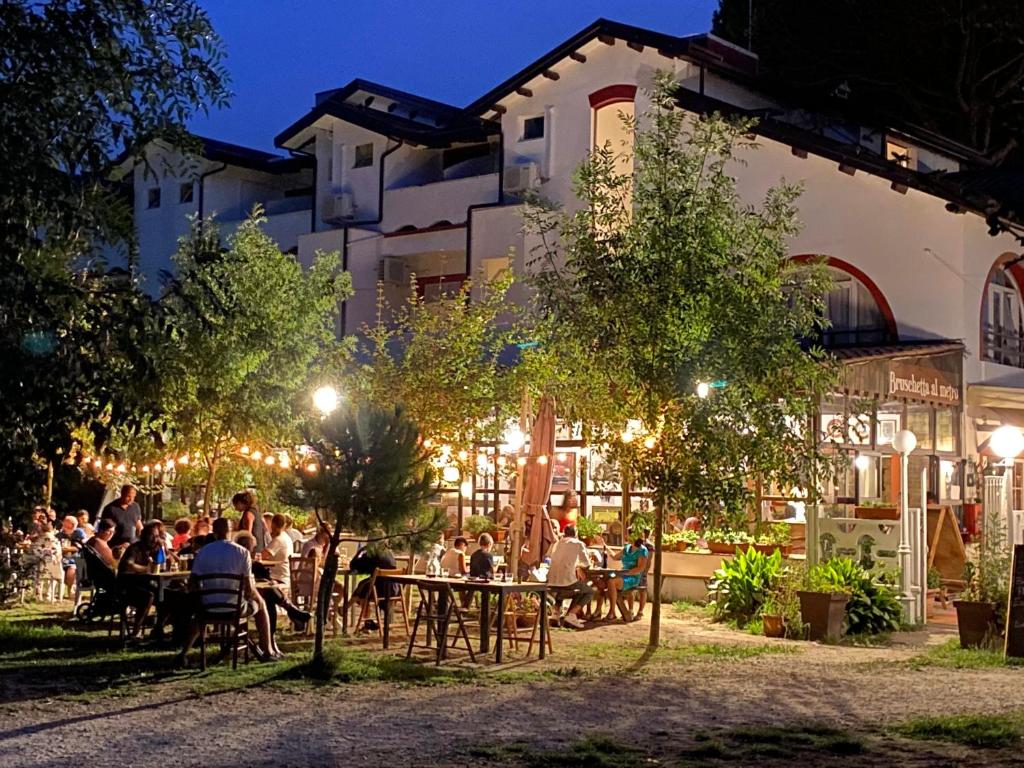 a group of people sitting at tables in front of a building at La Villa in Cervia