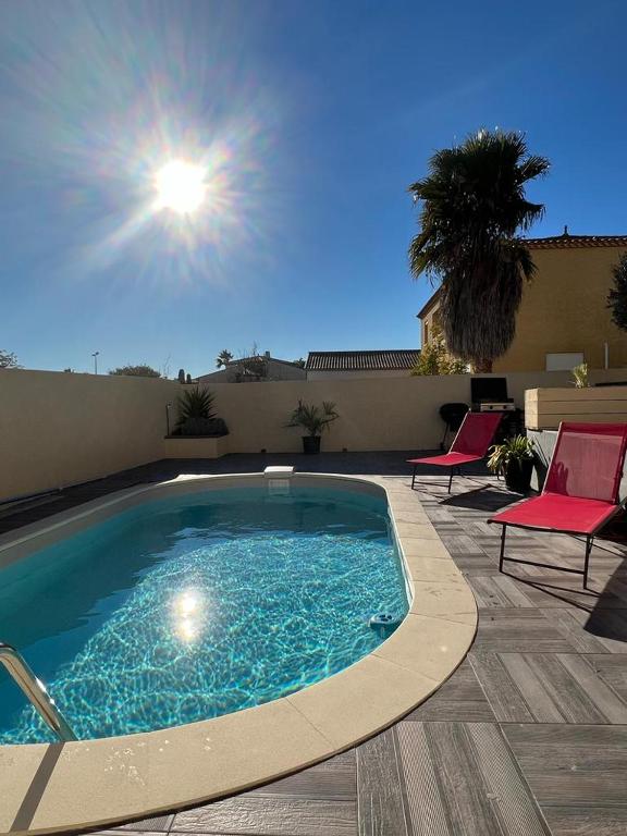 einen Pool auf einer Terrasse mit 2 Stühlen und einer Palme in der Unterkunft Maison avec piscine entièrement climatisée in Sauvian