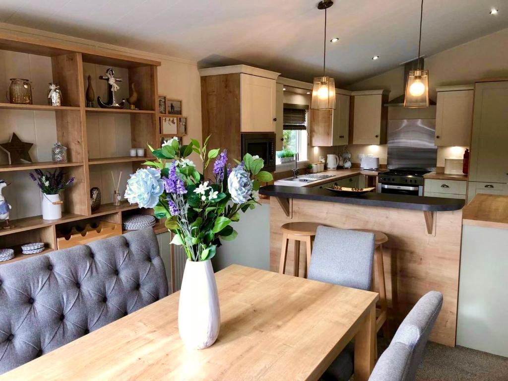 a vase of flowers on a wooden table in a kitchen at Griffon Lodge in Morpeth