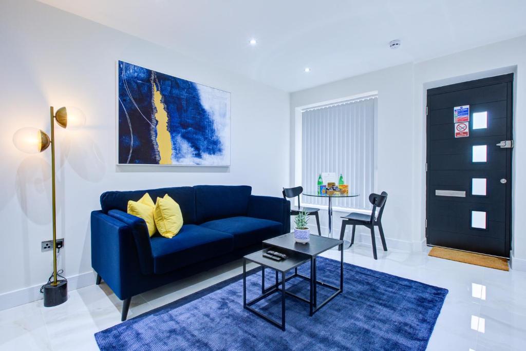 uma sala de estar com um sofá azul e uma mesa em Hybrid Resi - Uxbridge em Uxbridge