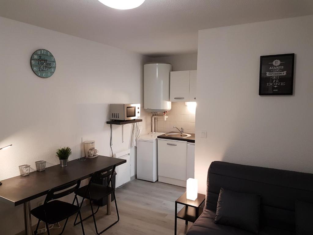 Il comprend un petit salon avec une table et une cuisine. dans l'établissement Studio meublé équipé paisible, à Chambray-lès-Tours