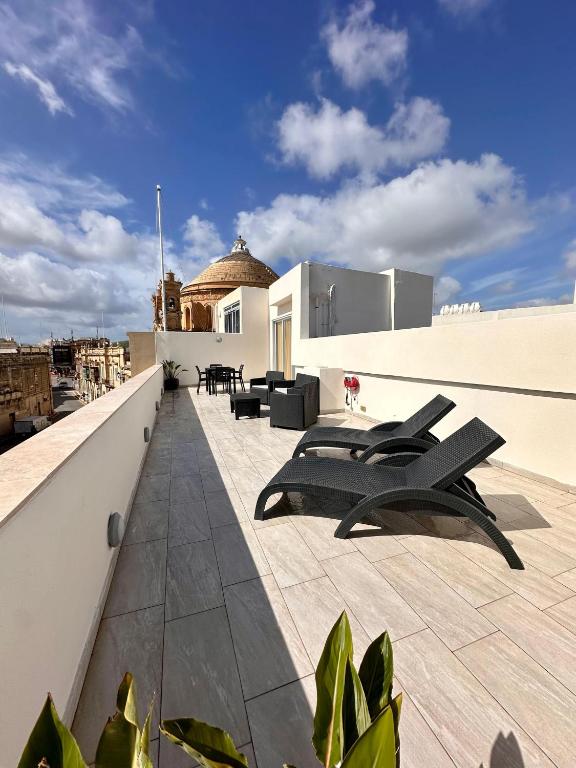 a balcony with chairs and tables on a building at Mosta Dome Penthouse in Mosta