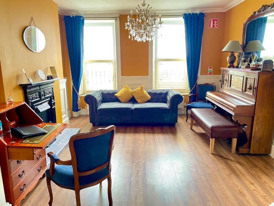 a living room with a blue couch and a piano at The Sardinian Guesthouse (6 Bedrooms) in Cobh