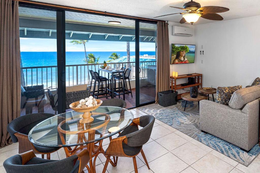 uma sala de estar com uma mesa de vidro e cadeiras em Kona Reef F23 em Kailua-Kona