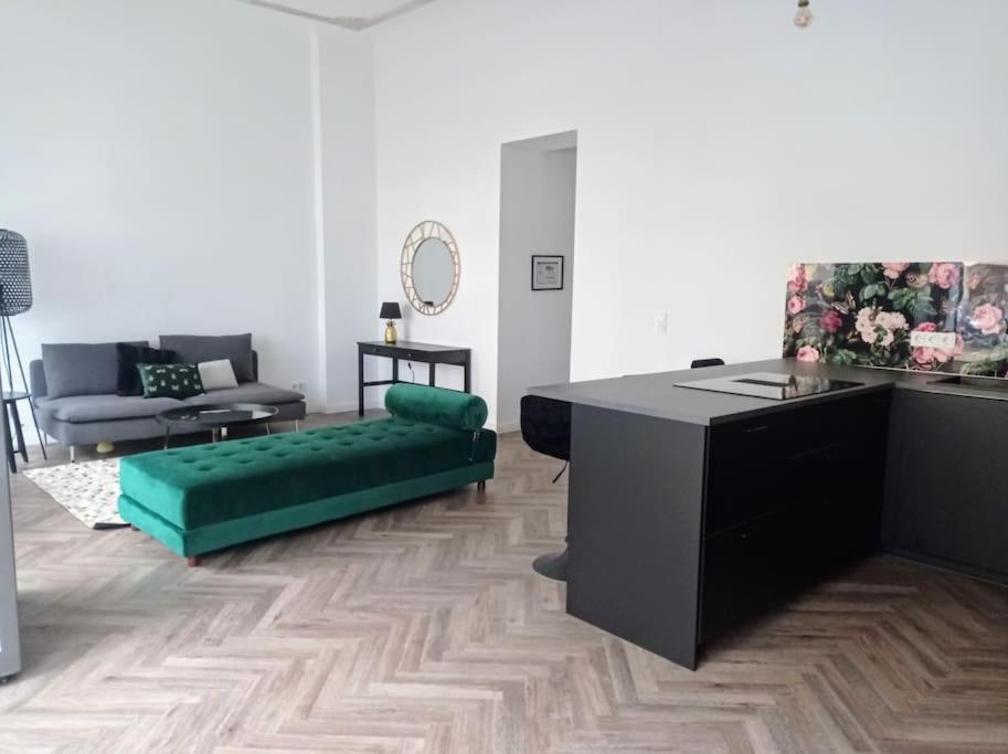 ein Wohnzimmer mit einem grünen Sofa und einem Tisch in der Unterkunft Loft nahe Schloss Charlottenburg in Berlin