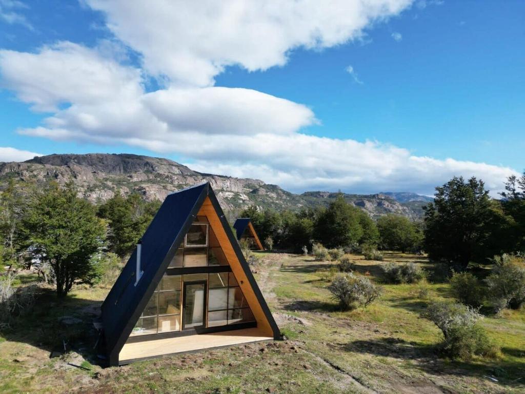 une petite maison avec un toit noir dans un champ dans l'établissement Precioso refugio en Villa Castillo Servicio Outscape, à Villa Cerro Castillo